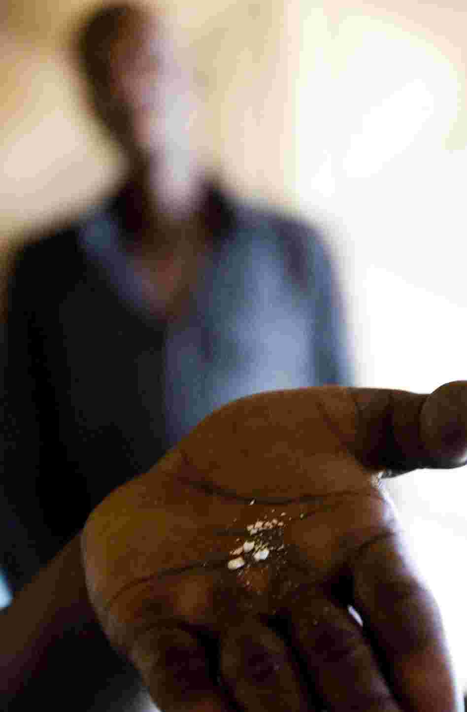 A whoonga smoker near Durban, South Africa, shows a crushed AIDS pill in the palm of his hand before mixing the drug with marijuana.
