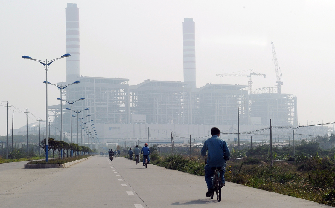 China and India are projected to propel coal's challenge of oil as the world's top energy source within the next five years, according to a new study. Here, a man rides a bicycle toward a coal-fired power station in China's Guangdong province last year.