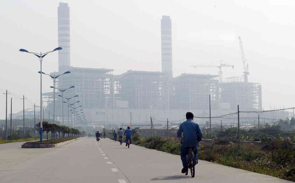 China and India are projected to propel coal's challenge of oil as the world's top energy source within the next five years, according to a new study. Here, a man rides a bicycle toward a coal-fired power station in China's Guangdong province last year.