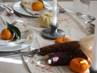 A dining table set for the holidays with linens, candlesticks, clementines and gourds. A dining table set for the holidays with linens, candlesticks, clementines and gourds.
