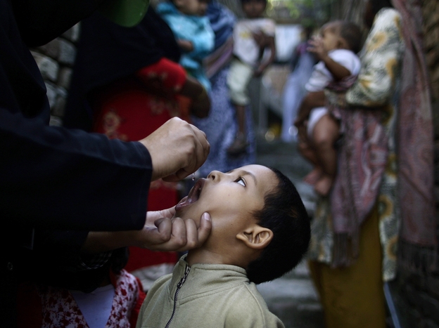 A Pakistani health worker gives a polio vaccine to a boy, while a group of women holding their children wait their turn, in an alley of a Christian neighborhood in Islamabad in October.
