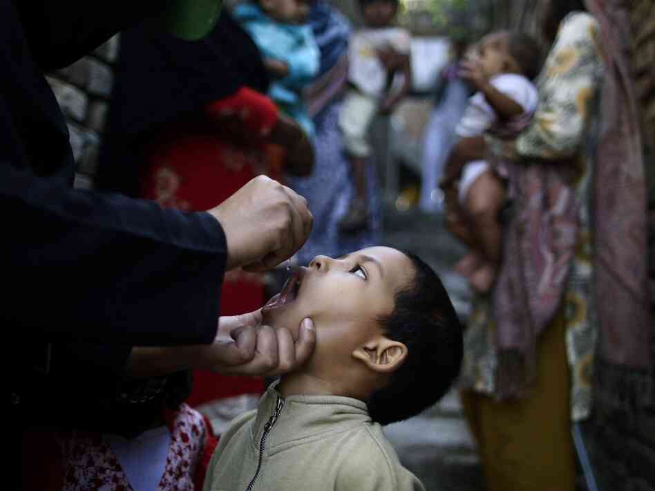 A Pakistani health worker gives a polio vaccine to a boy, while a group of women holding their children wait their turn, in an alley of a Christian neighborhood in Islamabad in October.