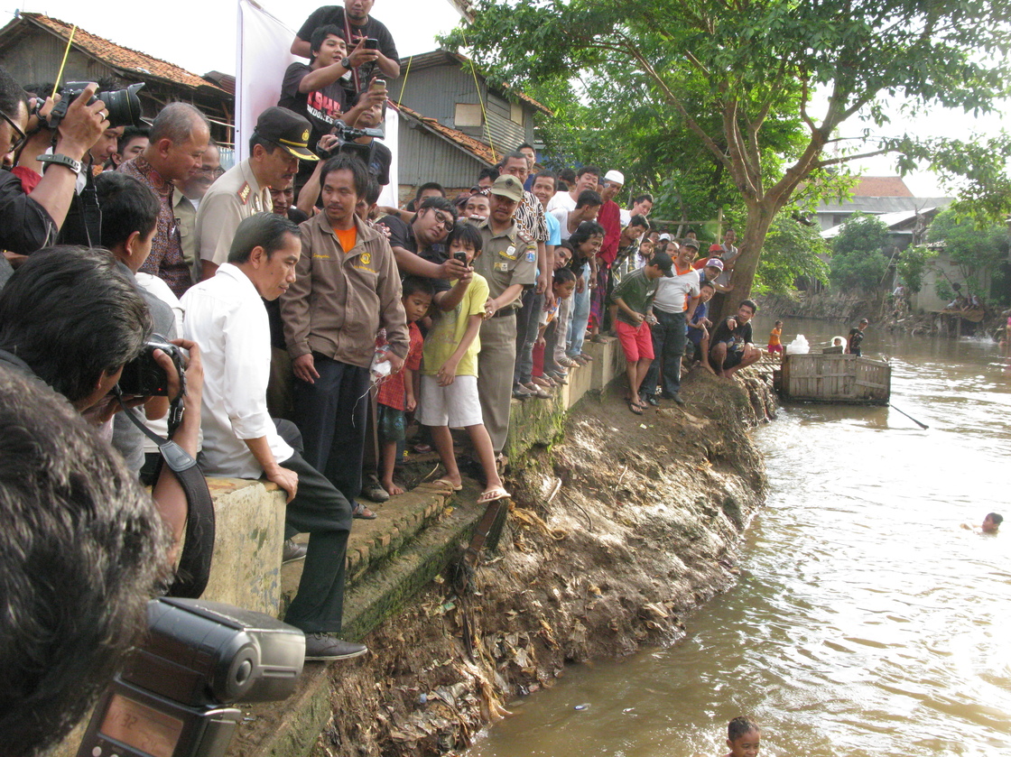 Jakarta Governor Joko Widodo (in white shirt, at left) examines the muddy waters of the Ciliwung River in Jakarta. The city government is planning to dredge the river and relocate residents away from its banks to prevent chronic urban flooding. His talk of providing more services has won him widespread popular support.