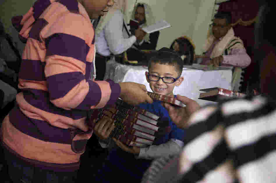 A boy collects books after prayers.