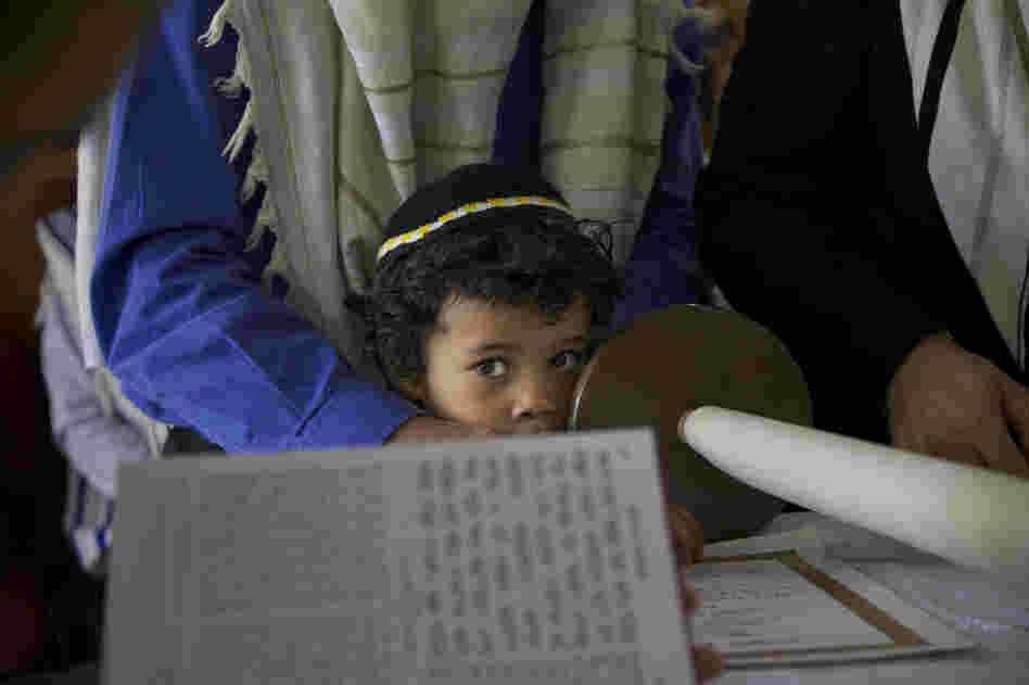 Baruj Cano, 4, watches as his father and other men from Bello's Jewish community read from the Torah.