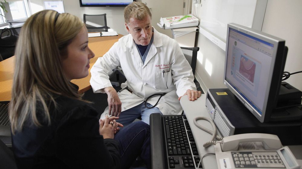 Kristen Miller, a colonoscopy patient, sits with Dr. Stephen Hanauer at the University of Chicago Medical Center in Chicago in 2010. They're looking at an interactive computer program describing benefits and risks of the procedure.