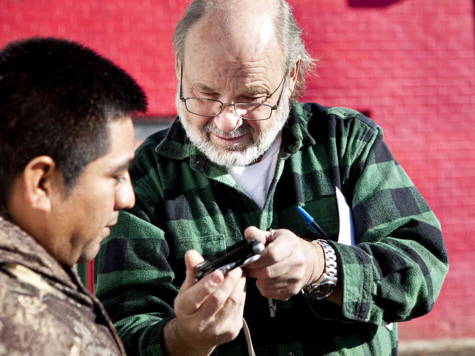 John Steinbach shows a day laborer in the parking lot of Ricos Tacos Moya a photo he took of him for an ID.