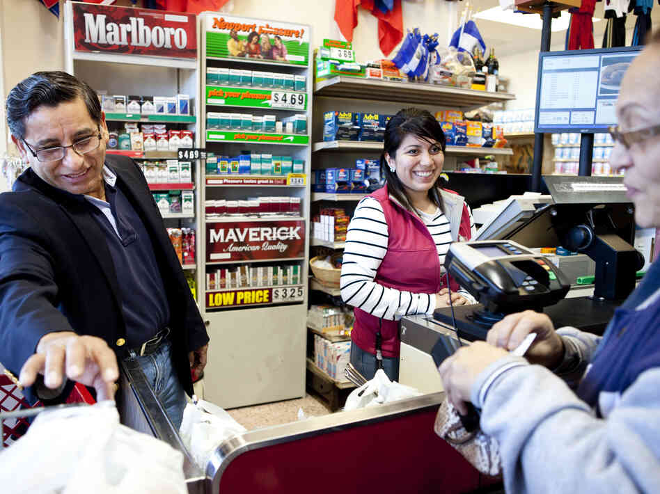Carlos Castro, owner of Todos Supermarket in Prince William County, chats with a customer at checkout.
