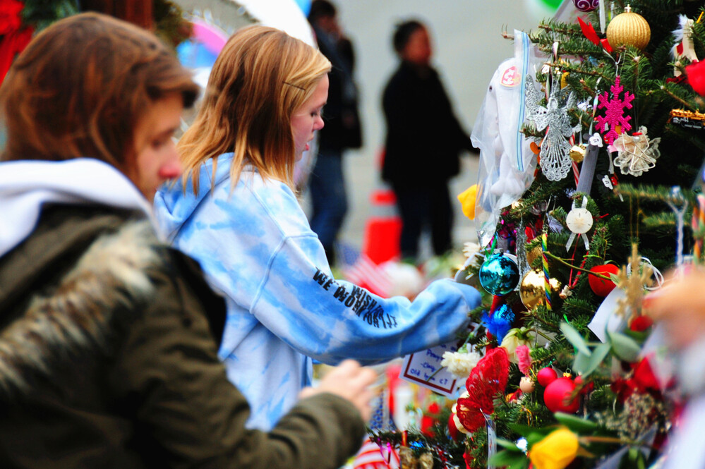 Mourners put decorations on a Christmas tree, part of a memorial in Newtown, Conn. Holiday greetings, toys and cards have flowed into the town, and some residents say the community feels closer-knit since the shooting.