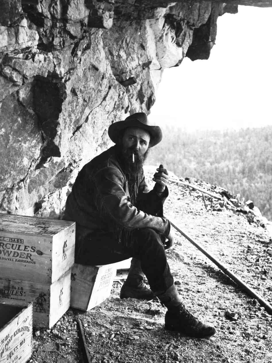 Sculptor Korczak Ziolkowski, who started the Crazy Horse memorial in 1948, smokes a cigarette near a crate of dynamite on a bluff of the Black Hills in 1950.