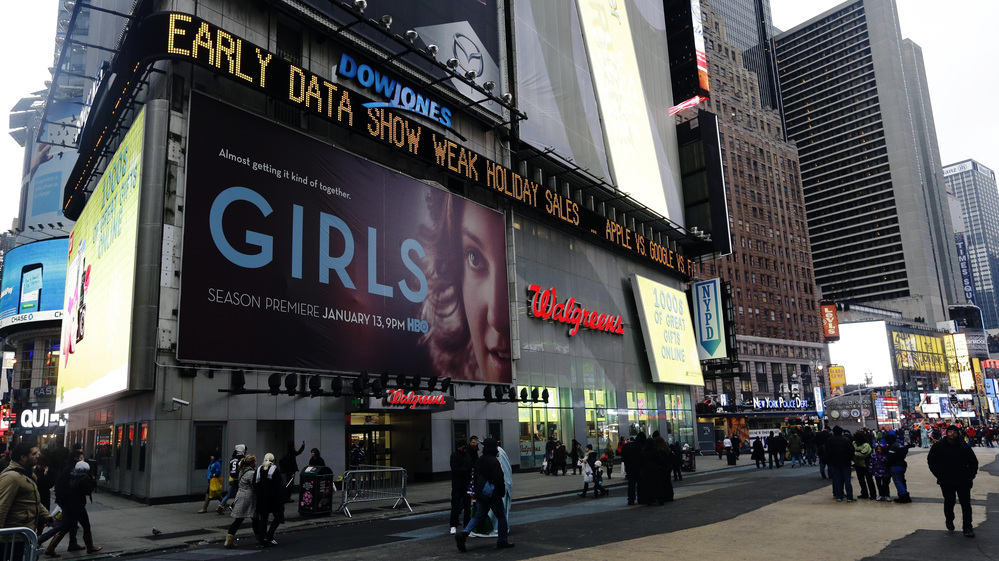Pedestrians pass the Dow Jones display ticker in Times Square on Wednesday in New York. U.S. shoppers spent cautiously this holiday season, a disappointment for retailers who slashed prices to lure people into stores and now must hope for a post-Christmas burst of spending.