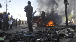 Rescuers carry a sheet to collect body parts near the scene of a bomb explosion in Karachi on Saturday that killed at least six people and . wounded 48. The sandals in the foreground are displayed for sale.