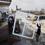 Contractors Benny Corrazo, left, and Michael Bonade install a new set of sliding glass doors in a home that survived Superstorm Sandy in the Breezy Point section of New York on Dec. 20, 2012. Some economists say that reconstruction efforts may stimulate the economy.