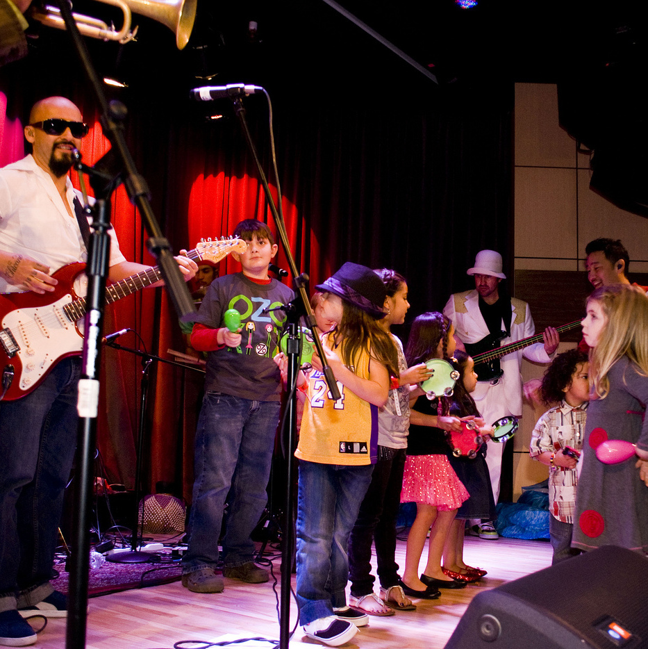 Ozomatli invites kids onstage for a performance.