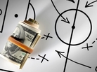 Roll of dollars on a blackboard with football strategy planning. Roll of dollars on a blackboard with football strategy planning.
