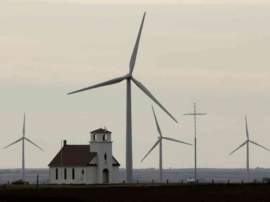 Wind turbines dwarf a church near Wilson, Kan. Although Congress voted to extend a wind energy tax credit, the temporary uncertainty dealt a blow to the industry.