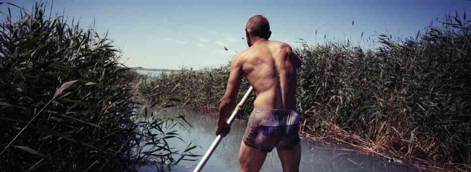 Vasily Sokolov steers his boat, July 2011. Vasily has been making a living mainly by fishing while living in the abandoned military barracks in the Sary-Shagan polygon. The Sokolov family is one of a few families living there.