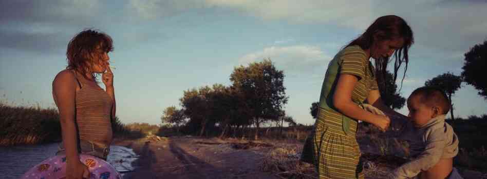 Tanya Sokolov dresses her son, Erasu, while Galya, who lived temporarily with the Sokolov family, smokes on the beach of Lake Balkhash, July 2011.