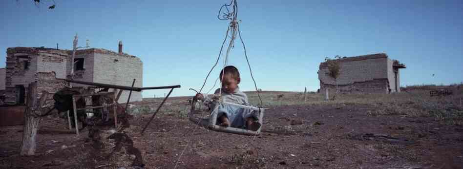 Erasu Sokolov sits in a swing by the former military barracks, which his family uses as a house, August 2011.