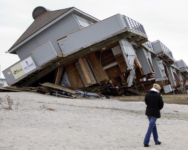 A woman walks past a cabana complex pulled off its foundations by Superstorm Sandy in Sea Bright, N.J., in November.