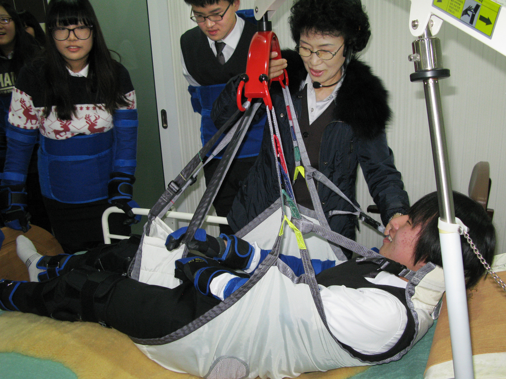 High school student Kim Dong-hyun undergoes a simulated experience as an incapacitated elderly person who is hoisted from his bed into a chair by means of a winch and sling. Training at the Seongnam Senior Complex outside Seoul is intended to help young people understand what the elderly are experiencing.