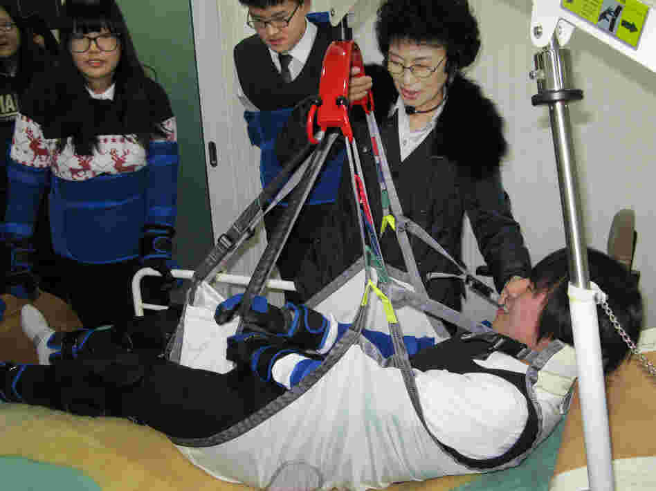 High school student Kim Dong-hyun undergoes a simulated experience as an incapacitated elderly person who is hoisted from his bed into a chair by means of a winch and sling. Training at the Seongnam Senior Complex outside Seoul is intended to help young people understand what the elderly are experiencing.