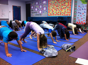 The third-graders at Olivenhain Pioneer take three deep breaths in the downward dog position during one of their two weekly yoga classes.