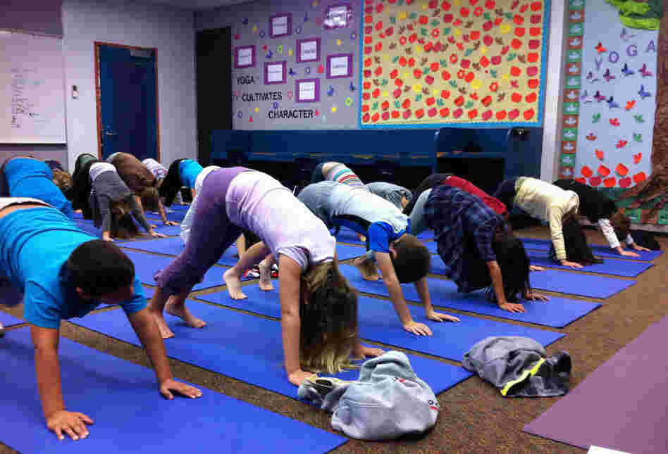 The third-graders at Olivenhain Pioneer take three deep breaths in the downward dog position during one of their two weekly yoga classes.