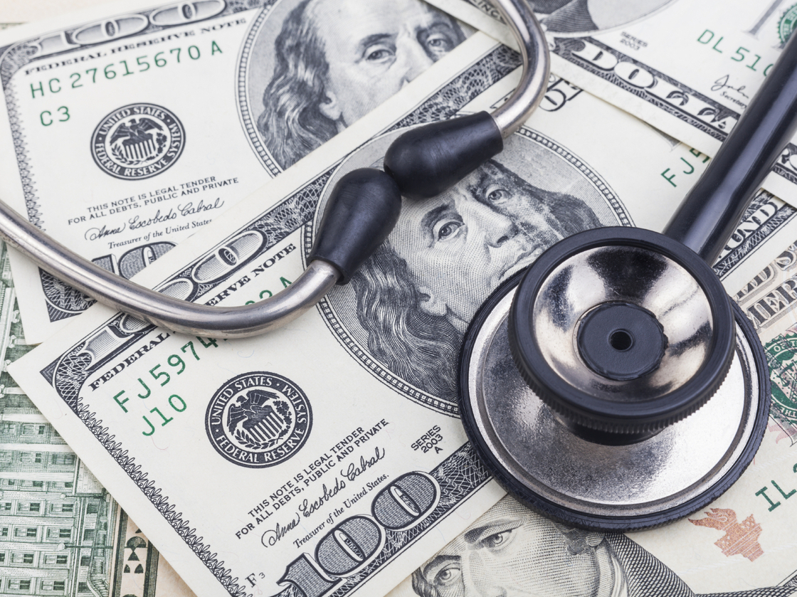 Black stethoscope close-up on top of dollar banknotes