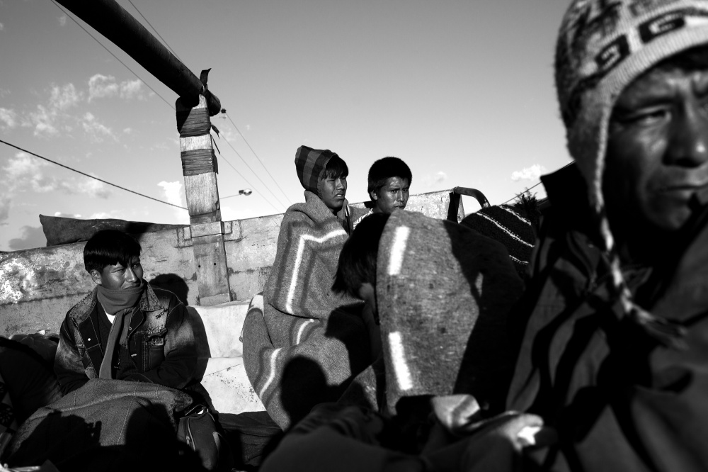 Teenage brothers Fredy and Saman Mamani (center) huddle together to stay warm as they travel atop a gas truck from the Andean crossroads town of Urcos, down into the Amazon Basin where they work in an informal gold mining camp.