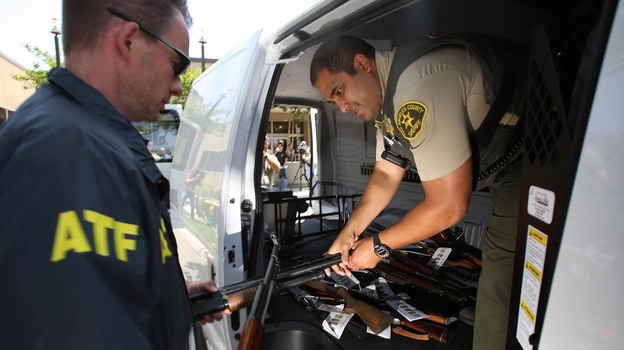 Officers transfer confiscated weapons after a news conference to announce the arrests of scores of alleged gang members and associates on federal racketeering and drug-trafficking charges in Lakewood, Calif., in 2009.