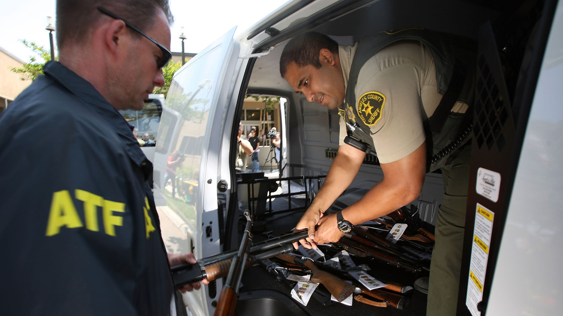 Officers transfer confiscated weapons after a news conference to announce the arrests of scores of alleged gang members and associates on federal racketeering and drug-trafficking charges in Lakewood, Calif., in 2009.