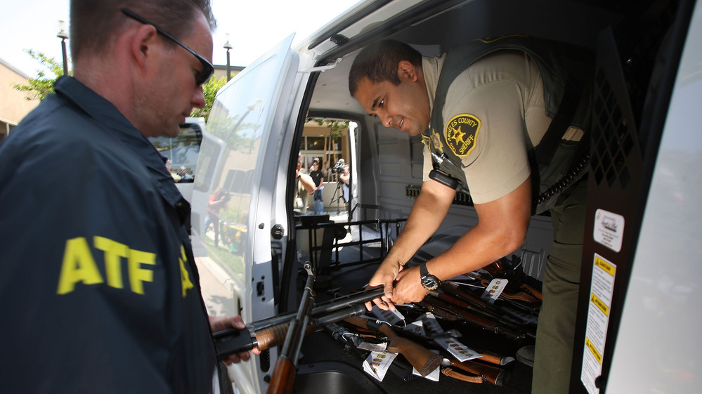 Officers transfer confiscated weapons after a news conference to announce the arrests of scores of alleged gang members and associates on federal racketeering and drug-trafficking charges in Lakewood, Calif., in 2009.