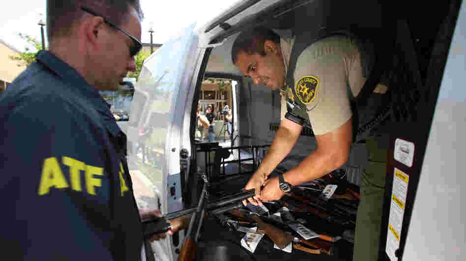 Officers transfer confiscated weapons after a news conference to announce the arrests of scores of alleged gang members and associates on federal racketeering and drug-trafficking charges in Lakewood, Calif., in 2009.