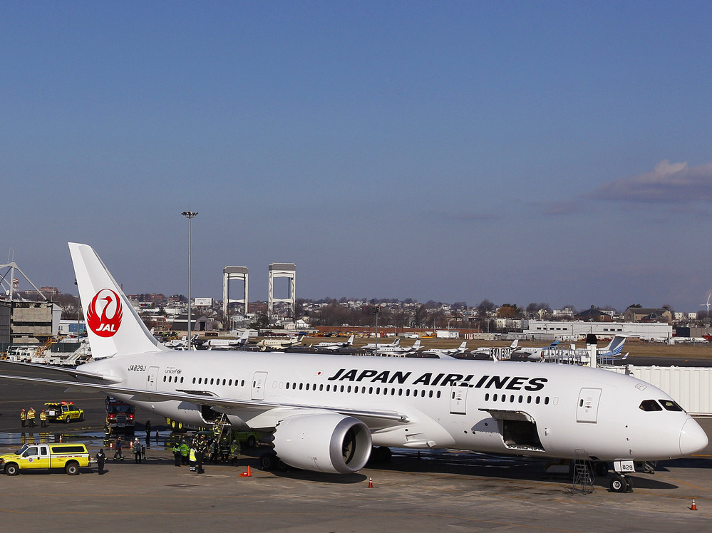A Japan Airlines Boeing 787 Dreamliner jet aircraft is surrounded by emergency vehicles while parked at a terminal E gate at Logan International Airport in Boston on Monday. A small electrical fire filled the cabin of the JAL aircraft with smoke about 15 minutes after it landed in Boston.