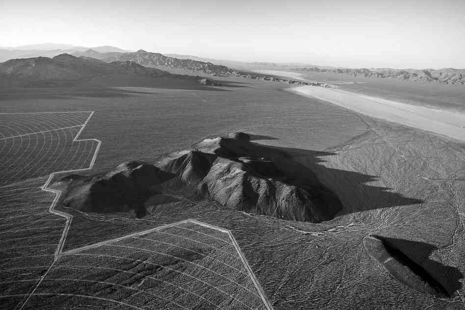 The boundaries of Solar Fields Two and Three move around existing geological formations protruding above the alluvial slope of Ivanpah Basin. Interstate 15 crosses the distant dry lake bed, and Primm, Nev., is seen in the distance. June 2012.