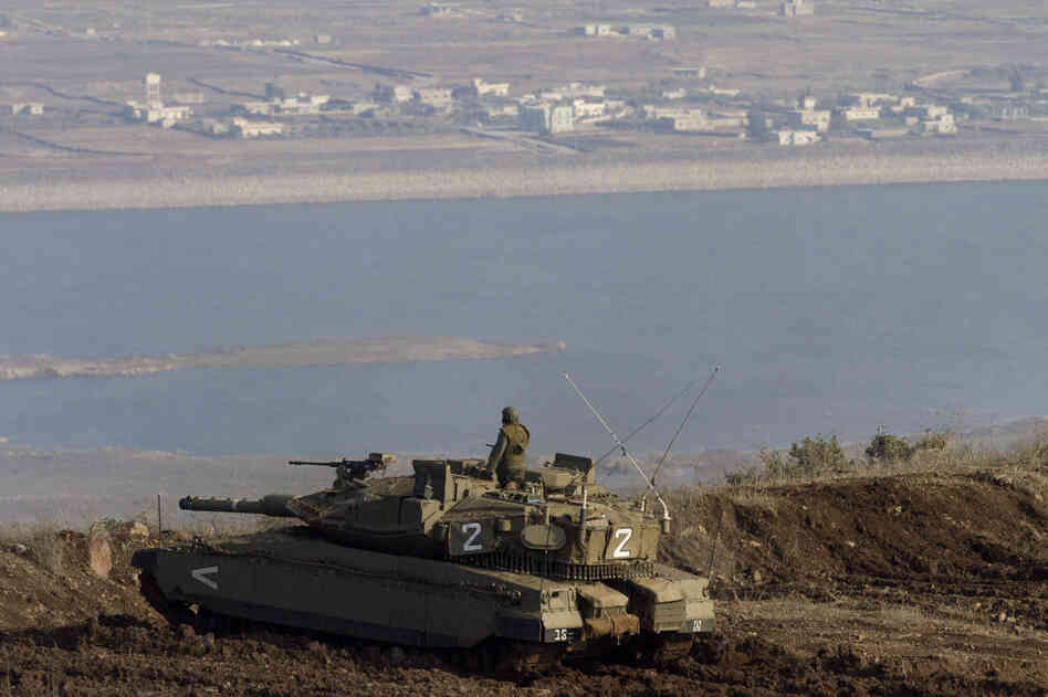 An Israeli tank in the Golan Heights overlooks the Syrian village of Bariqa in November. Israel, which captured the Golan Heights from Syria in 1967, says it's building a fence there because it's concerned about spillover from the Syrian war.
