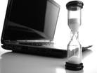 Wide angle shot of an hourglass with laptop computer in the background. Wide angle shot of an hourglass with laptop computer in the background.