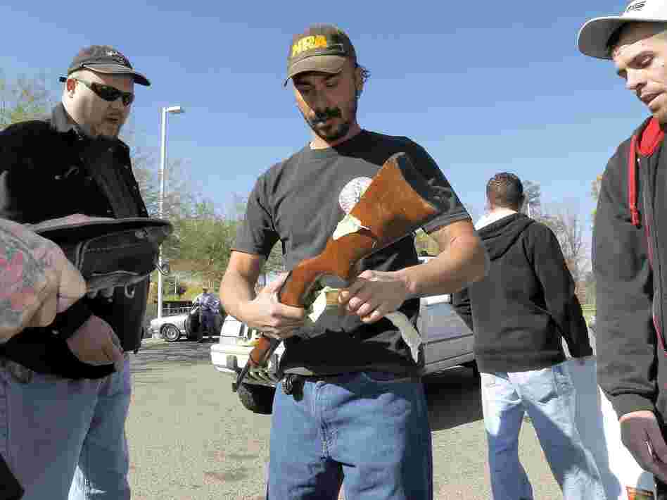 Gun buyers inspect their purchases outside a police station in Tucson, Ariz., on Tuesday. About a dozen buyers offered cash to sellers in the parking lot of a police station where a city councilman had set up a gun buyback program.