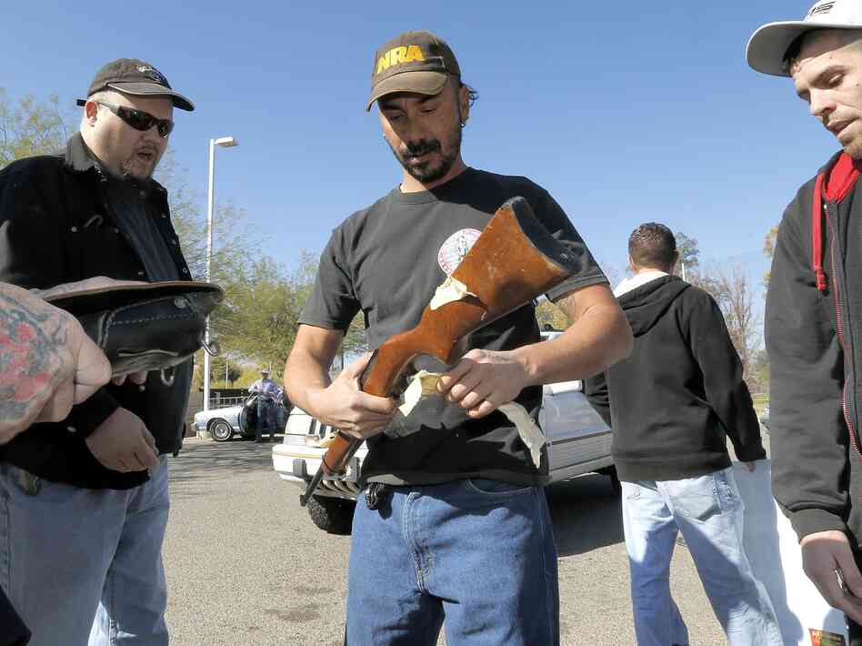 Gun buyers inspect their purchases outside a police station in Tucson, Ariz., on Tuesday. About a dozen buyers offered cash to sellers in the parking lot of a police station where a city councilman had set up a gun buyback program.