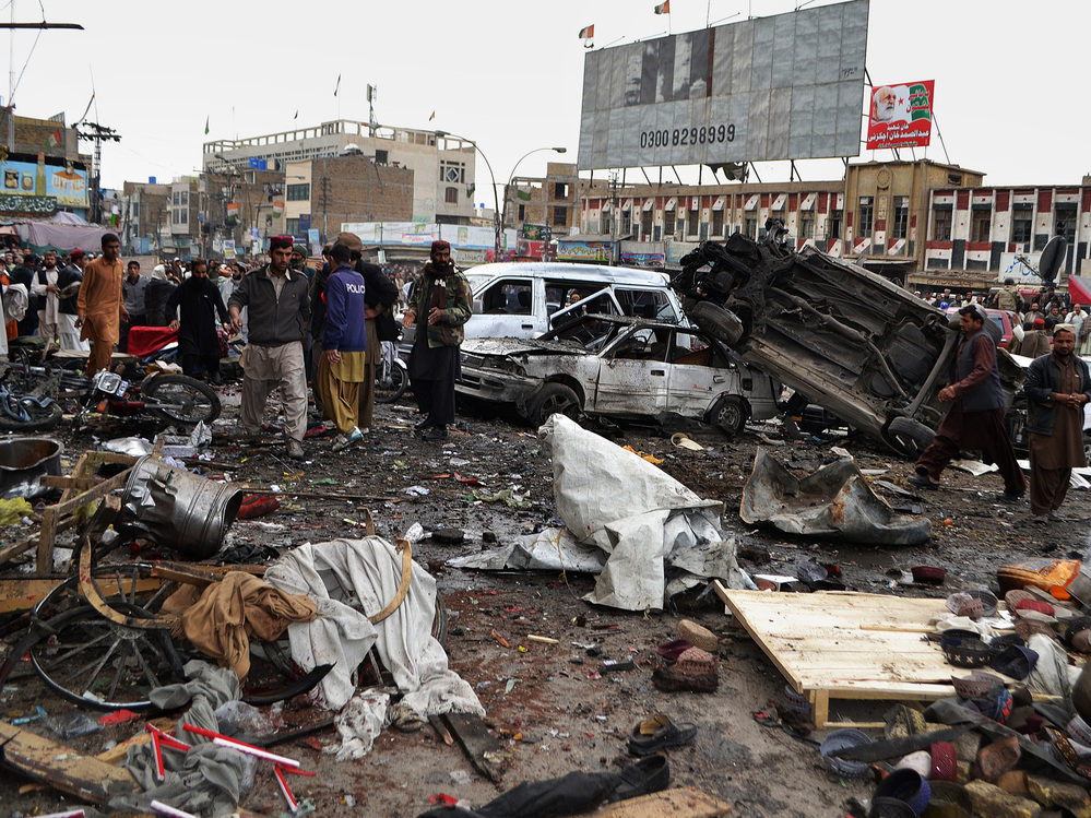 Pakistani police officers and residents gather at the site of a bomb blast that targeted paramilitary soldiers in a commercial area in the city of Quetta, killing 11 people. Later in the day, twin blasts at a snooker club in the city killed at least 80 people.