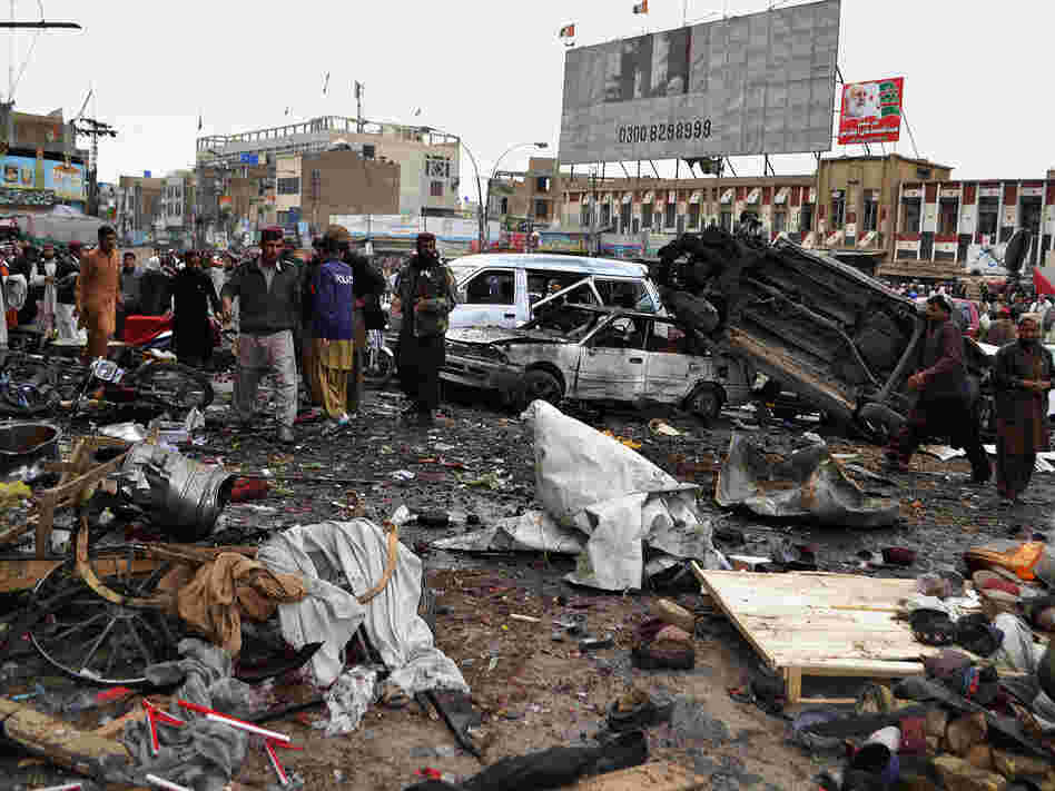 Pakistani police officers and residents gather at the site of a bomb blast that targeted paramilitary soldiers in a commercial area in the city of Quetta, killing 11 people. Later in the day, twin blasts at a snooker club in the city killed at least 80 people.