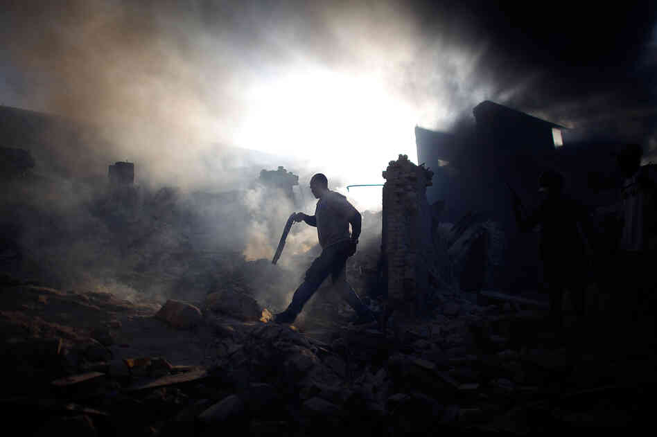 A man carrying a shotgun looks to keep looters at bay in the commercial district of downtown Port-au-Prince, Haiti, Jan. 18, 2010.