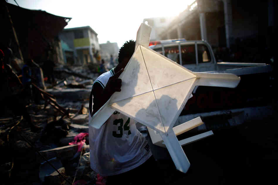 A man carries a stolen plastic table past a police car in Port-au-Prince, Haiti, Jan. 20, 2010.