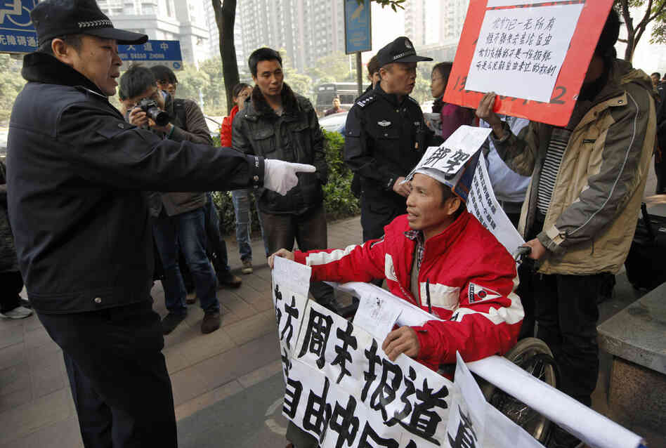 A policeman points to a supporter of Southern Weekly before taking him away during a protest near the newspaper's headquarters Thursday.