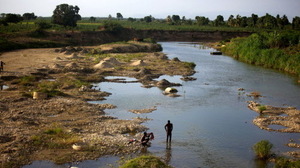 Men bathe in a branch of the Artibonite River outside Saint-Marc. Haiti's cholera outbreak in 2010 began about 60 miles upstream from here.