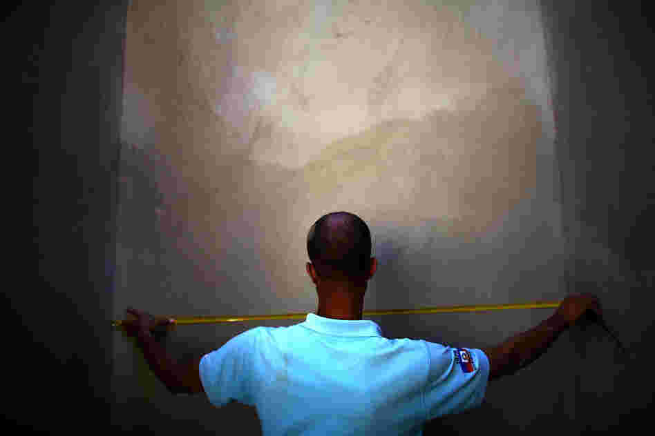 A man measures a completed section of a retaining wall at a construction site in the hills above Port-au-Prince near Petionville.