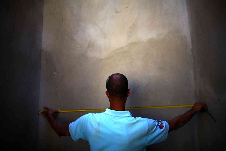 A man measures a completed section of a retaining wall at a construction site in the hills above Port-au-Prince near Petionville.