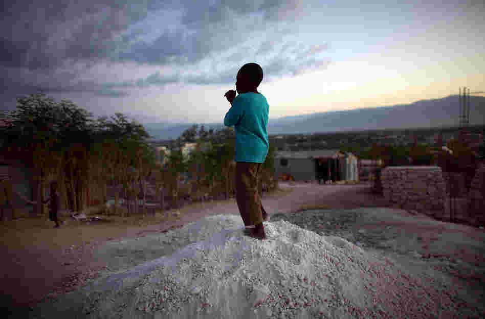 A boy stands on a pile of rocks used for the construction of new homes in the hills overlooking Camp Corail, just north of Port-au-Prince. Squatters are streaming into the area and setting up communities, with little government oversight.