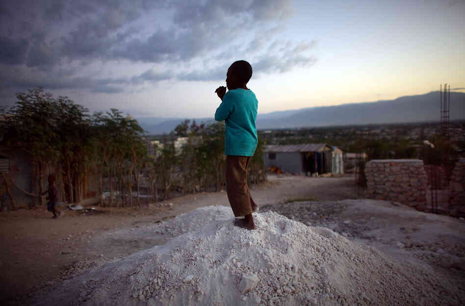 A boy stands on a pile of rocks used for the construction of new homes in the hills overlooking Camp Corail, just north of Port-au-Prince. Squatters are streaming into the area and setting up communities, with little government oversight.